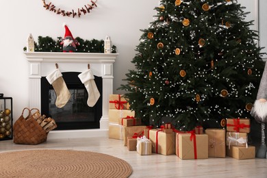 Photo of Many different gift boxes under Christmas tree and festive decor in living room