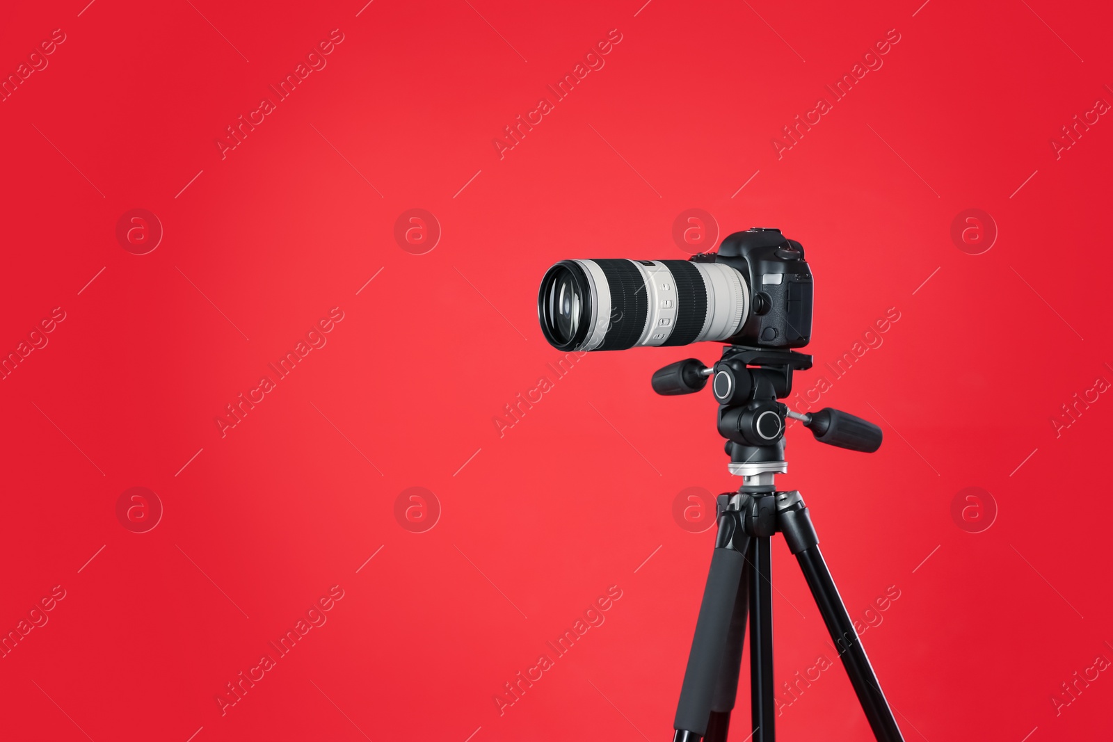 Photo of Modern professional video camera on red background