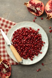 Photo of Tasty ripe pomegranate and grains on grey table, flat lay