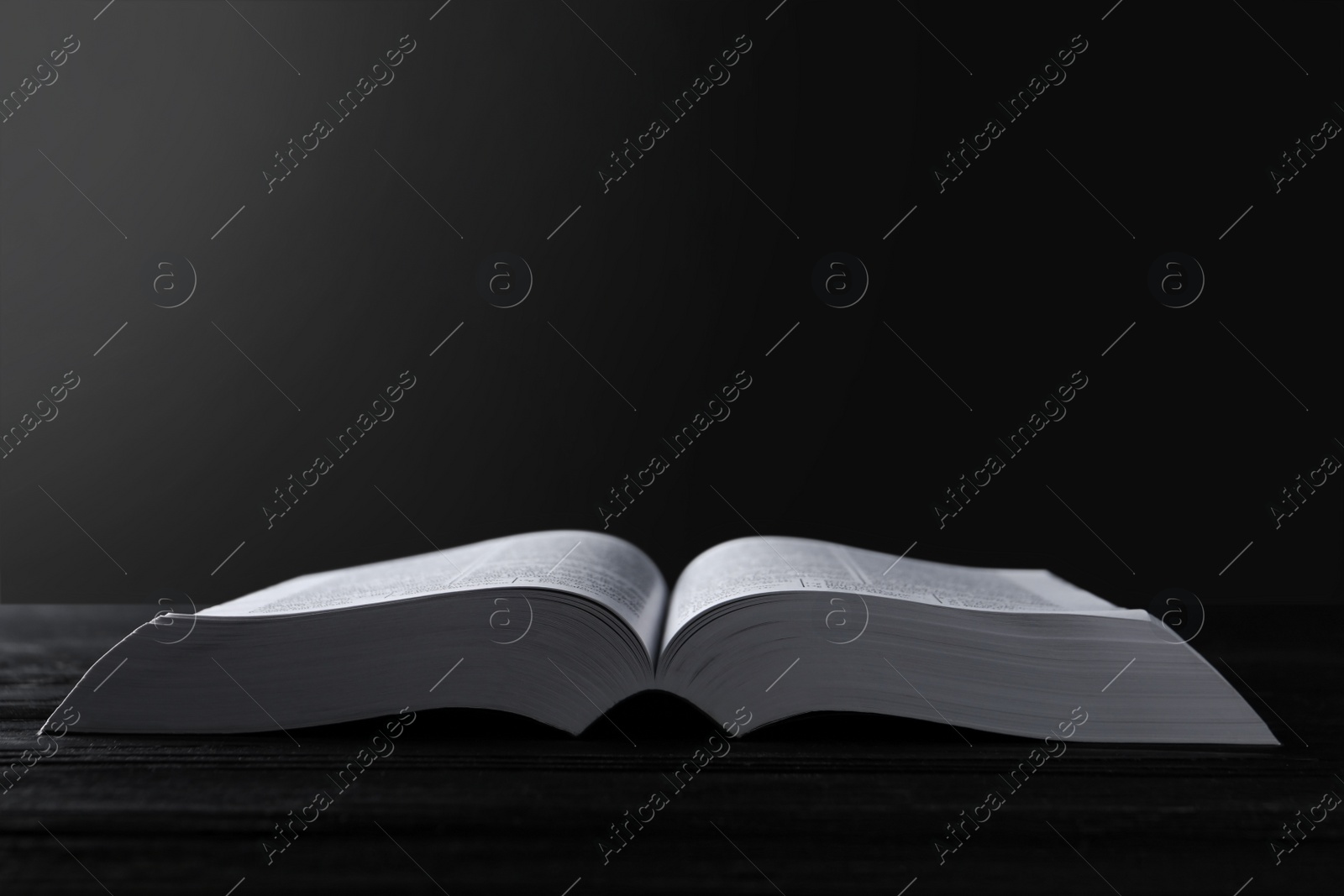 Photo of Open Bible on black wooden table. Christian religious book