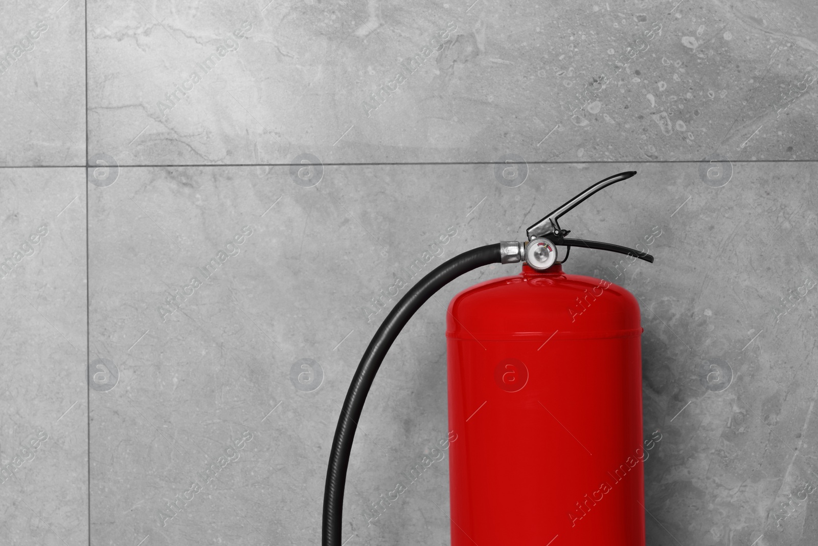 Photo of Fire extinguisher near grey wall, space for text