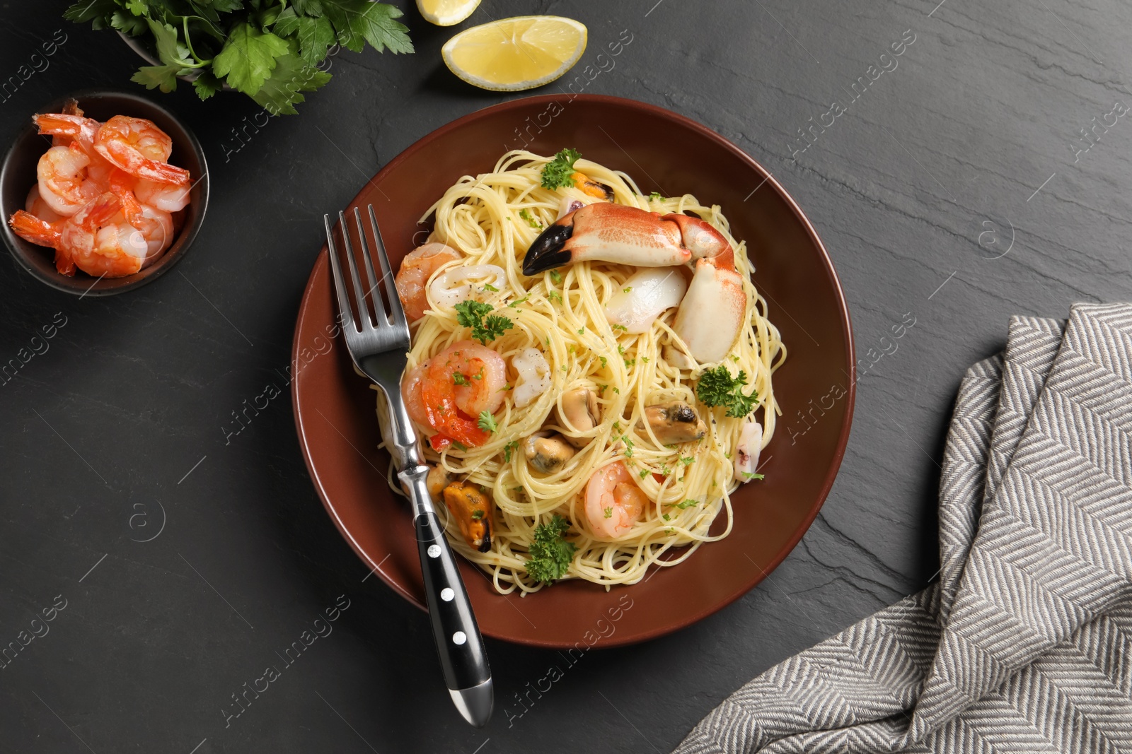 Photo of Delicious pasta with sea food served on black table, flat lay