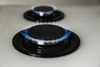 Photo of Gas burner with blue flame on modern stove, closeup