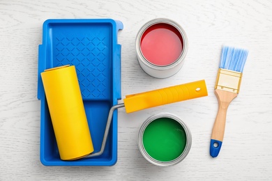 Flat lay composition with cans of paint, brush and renovation tools on white wooden background