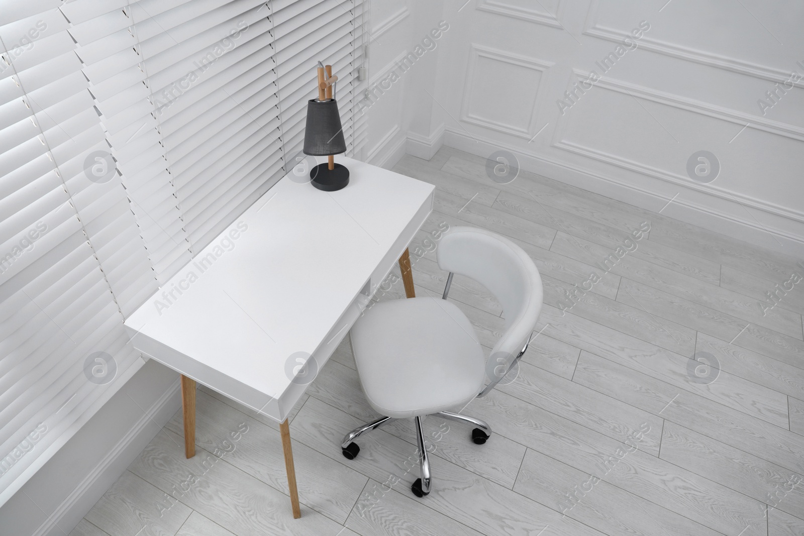 Photo of Stylish workplace with white desk and comfortable chair near window indoors. Interior design