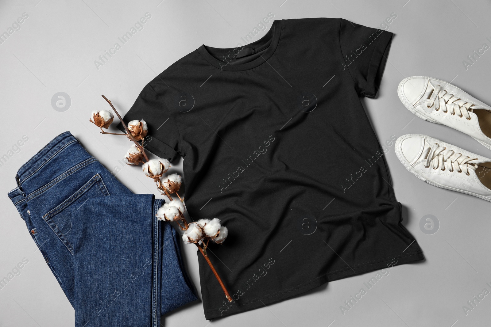 Photo of Stylish t-shirt, jeans and sneakers on light grey background, flat lay