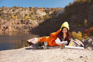 Photo of Female camper in sleeping bag reading book outdoors. Space for text