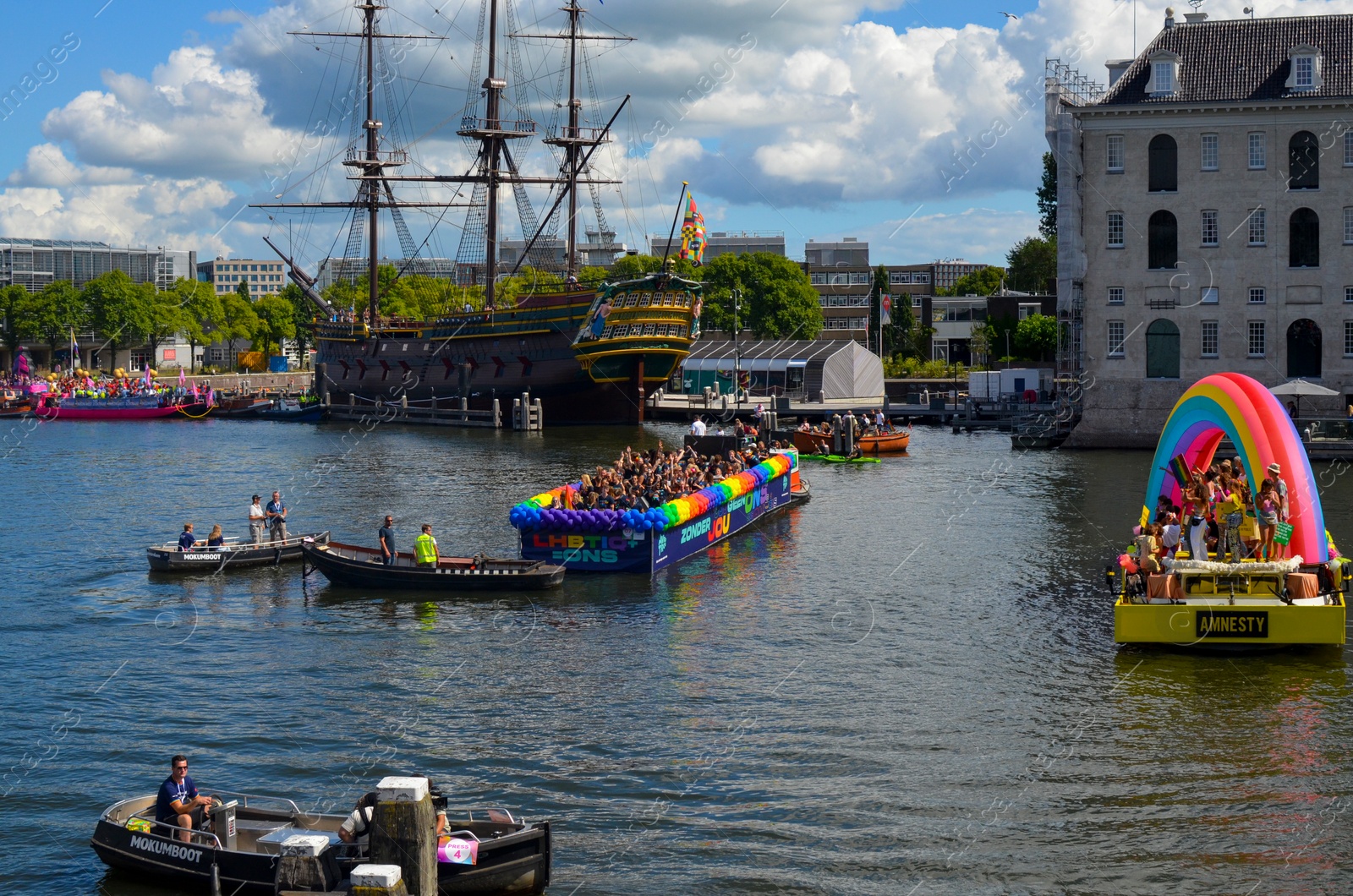 Photo of AMSTERDAM, NETHERLANDS - AUGUST 06, 2022: Many people in boats at LGBT pride parade on river