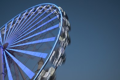 Big glowing Ferris wheel against blue sky, low angle view. Space for text