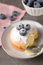 Photo of Tasty vanilla fondant with white chocolate and blueberries on grey table