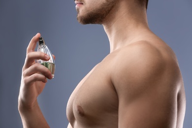 Photo of Handsome man using perfume on grey background, closeup