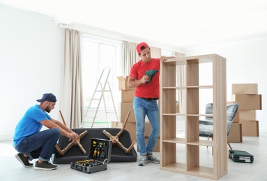 Male movers assembling furniture in new house