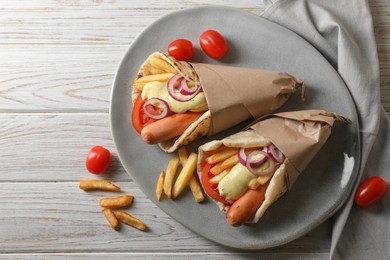 Delicious pita wrap with sausages, vegetables and potato fries on white wooden table, flat lay. Space for text