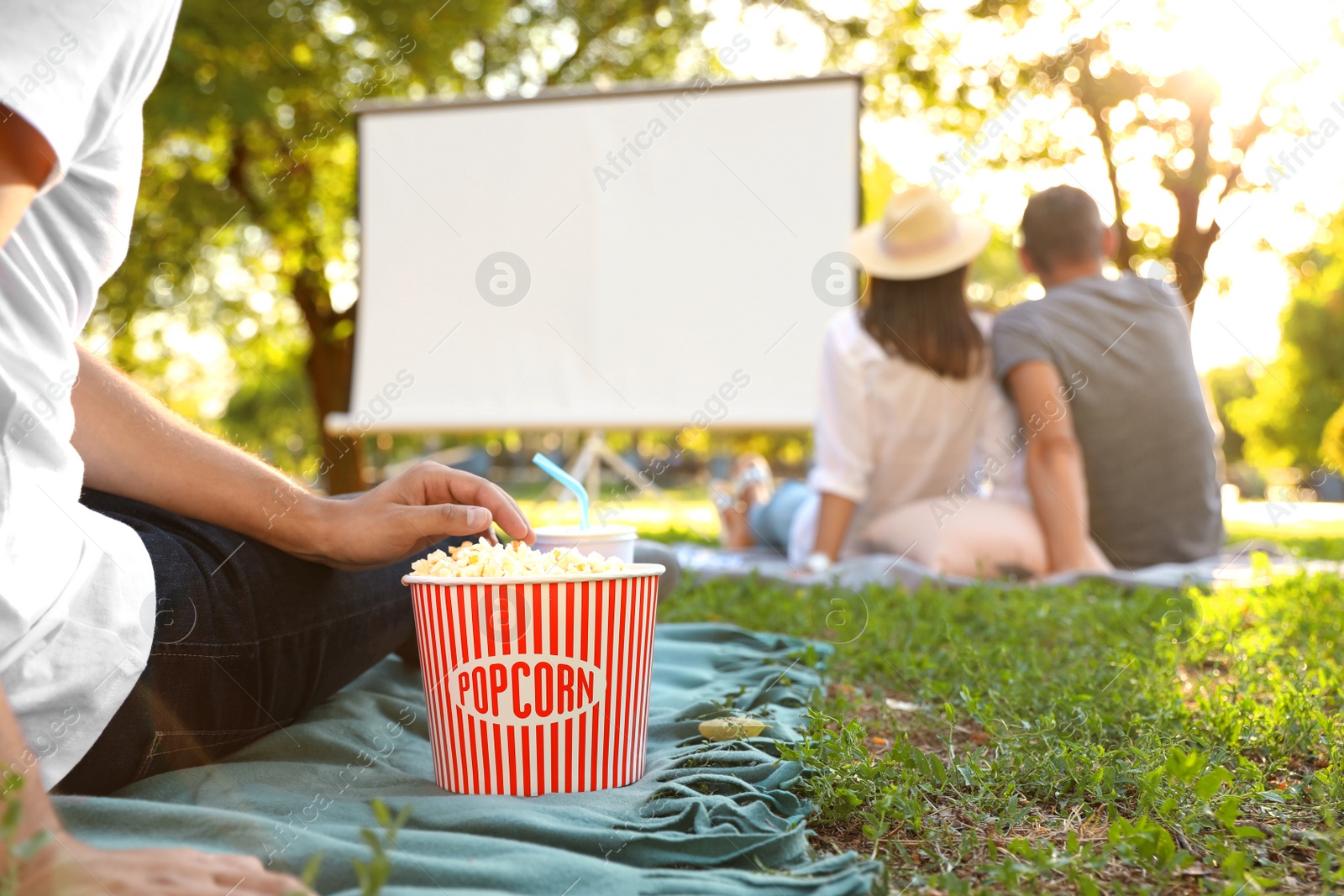 Photo of Young man with popcorn watching movie in open air cinema, closeup. Space for text