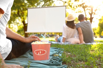 Photo of Young man with popcorn watching movie in open air cinema, closeup. Space for text