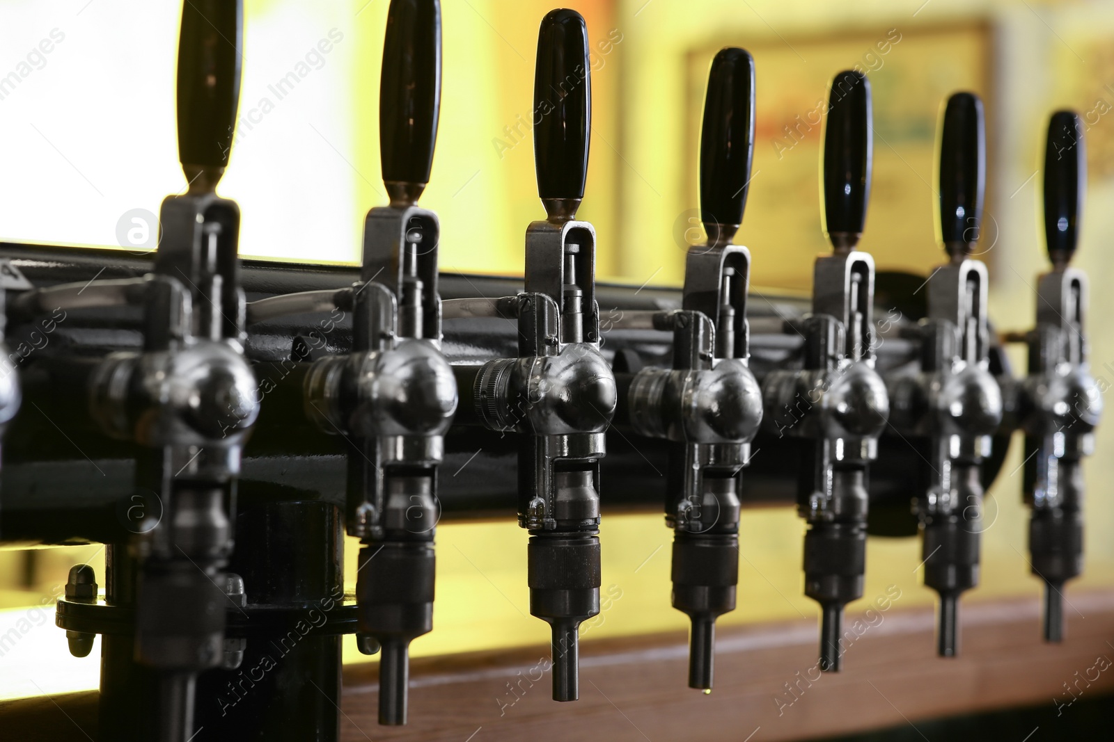 Photo of New modern beer taps in pub, closeup. Professional bar equipment