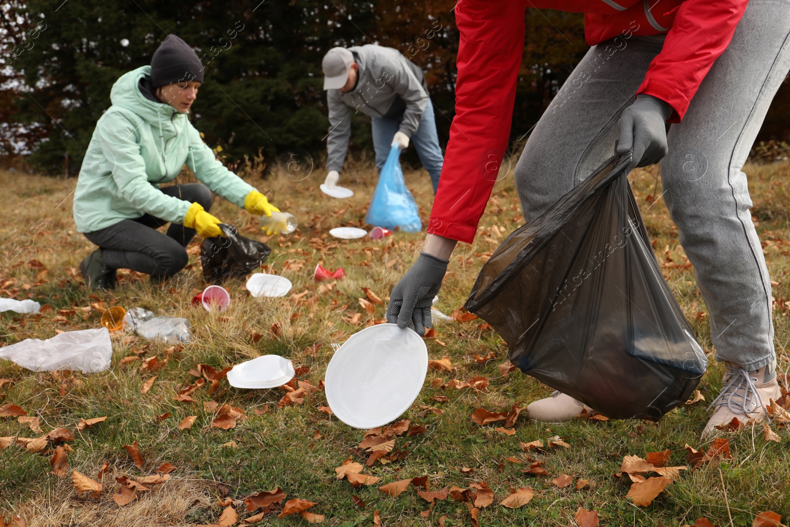 Photo of People with trash bags collecting garbage in nature, closeup