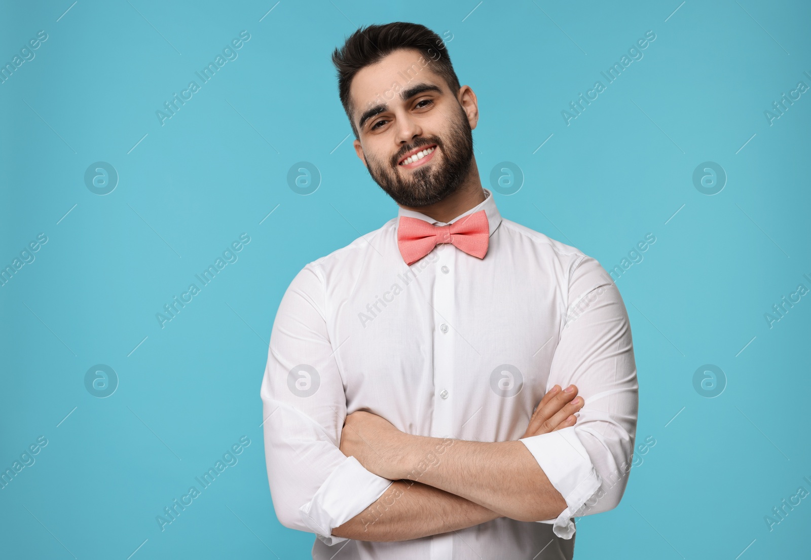 Photo of Portrait of smiling man in shirt and bow tie on light blue background