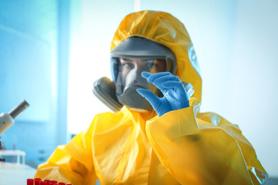 Scientist in chemical protective suit with microscope slide at laboratory. Virus research