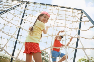 Photo of Cute children on playground rope climber outdoors. Summer camp
