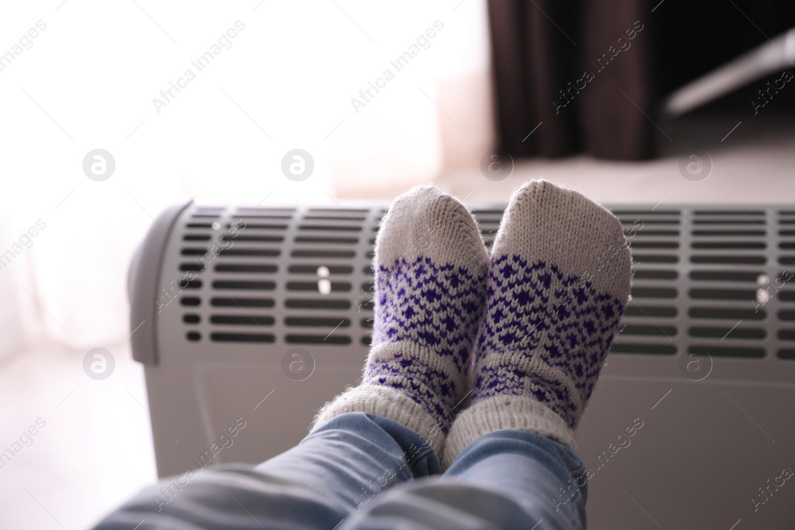 Photo of Child warming feet on electric heater at home, closeup