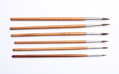 Different paint brushes on white background, top view