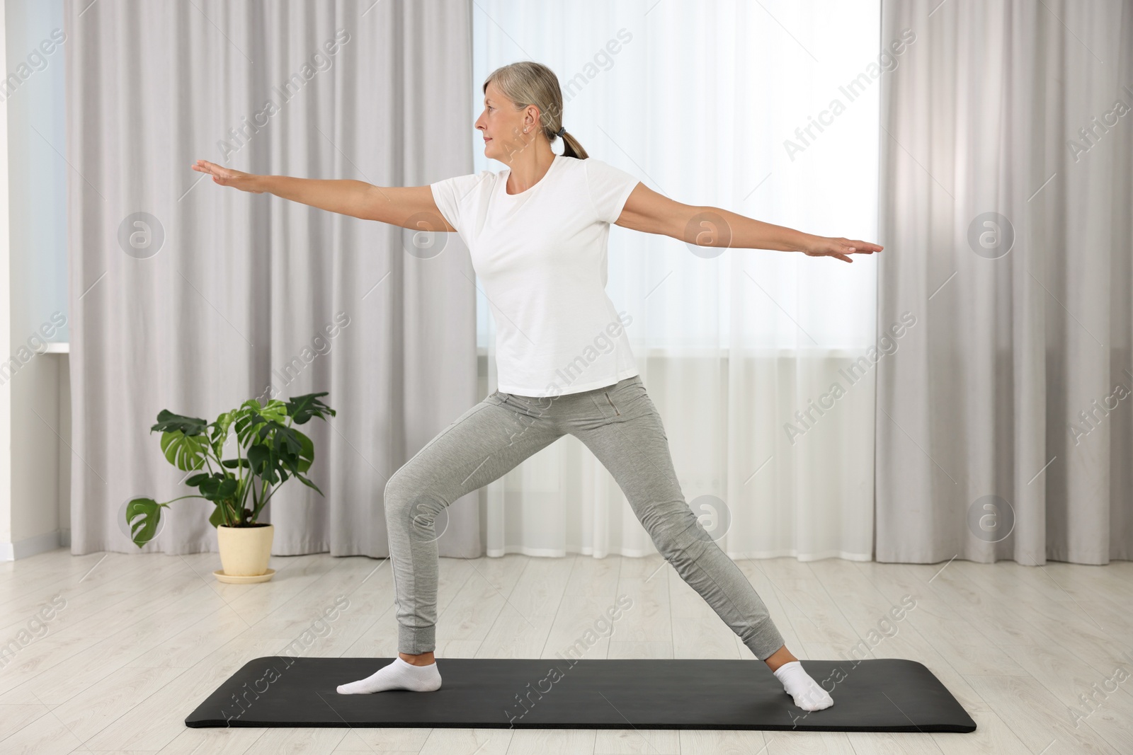 Photo of Senior woman practicing yoga on mat at home