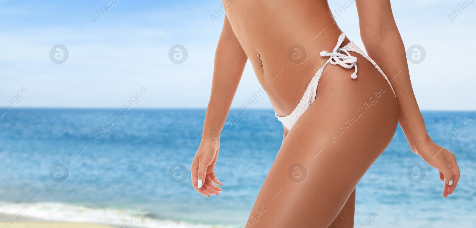 Image of Sexy young woman wearing stylish bikini near ocean on sunny day, closeup. Banner design