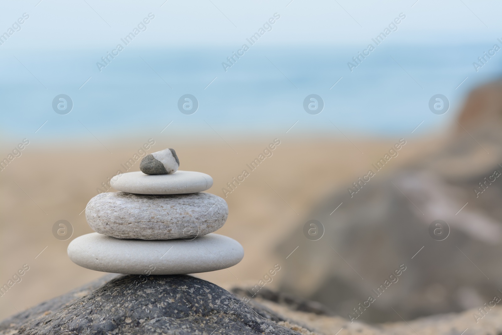 Photo of Stack of stones on rock near sea, space for text