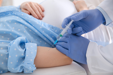 Photo of Doctor giving injection to pregnant woman in hospital, closeup. Vaccination concept