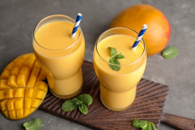 Photo of Glasses of fresh mango drink and fruits on table