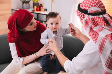 Happy Muslim family with little son in living room