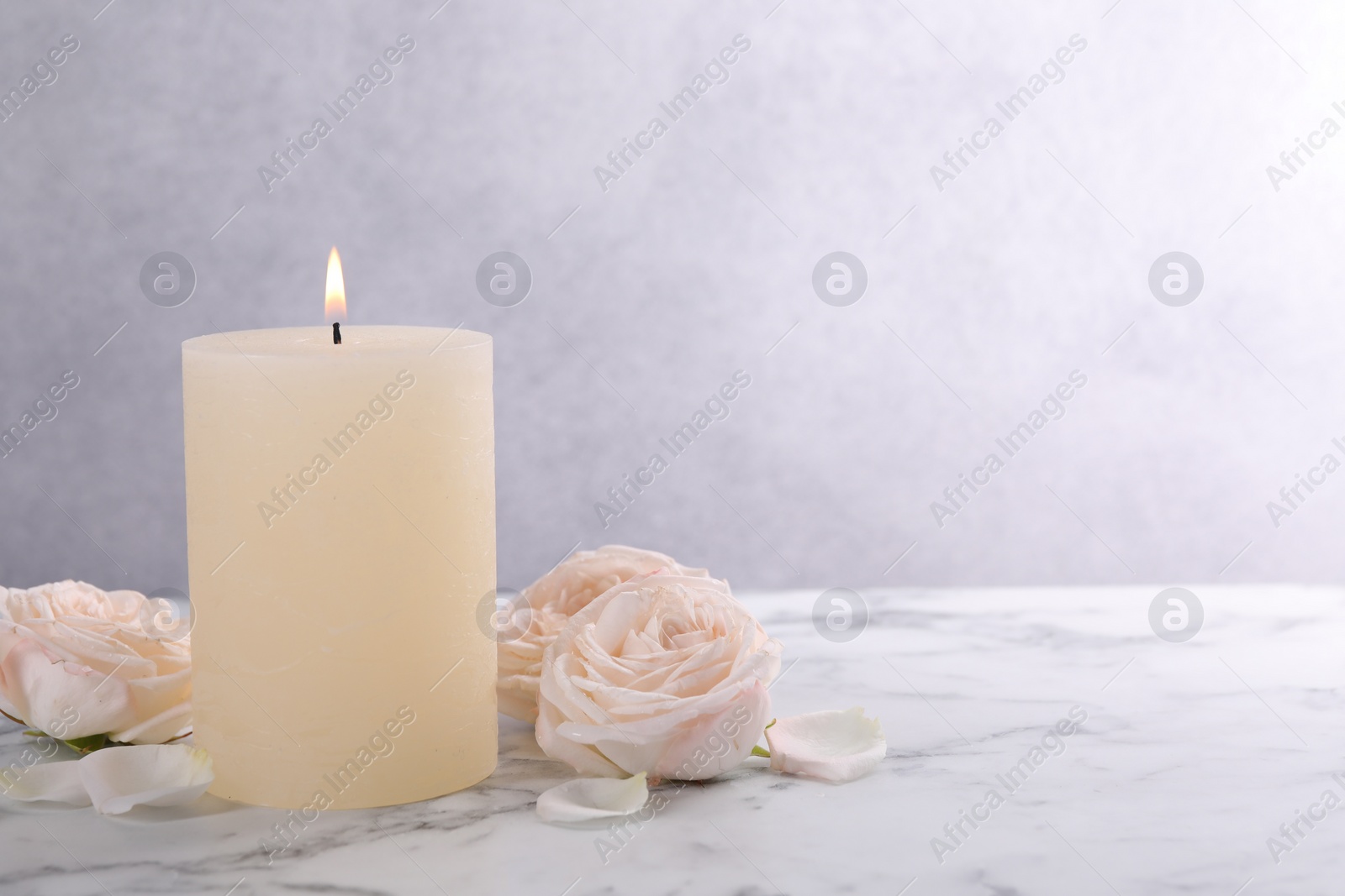 Photo of Spa composition with burning candle and flowers on white marble table, space for text