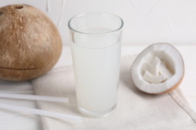 Photo of Glass of coconut water and nuts on white table