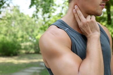 Photo of Young man checking pulse after training outdoors, closeup