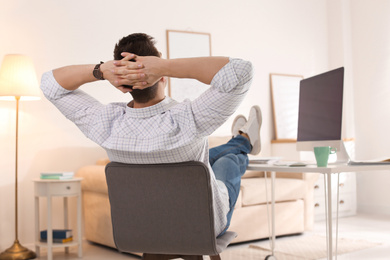 Young man relaxing at table in office during break