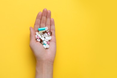 Photo of Woman holding antidepressants on yellow background, top view. Space for text