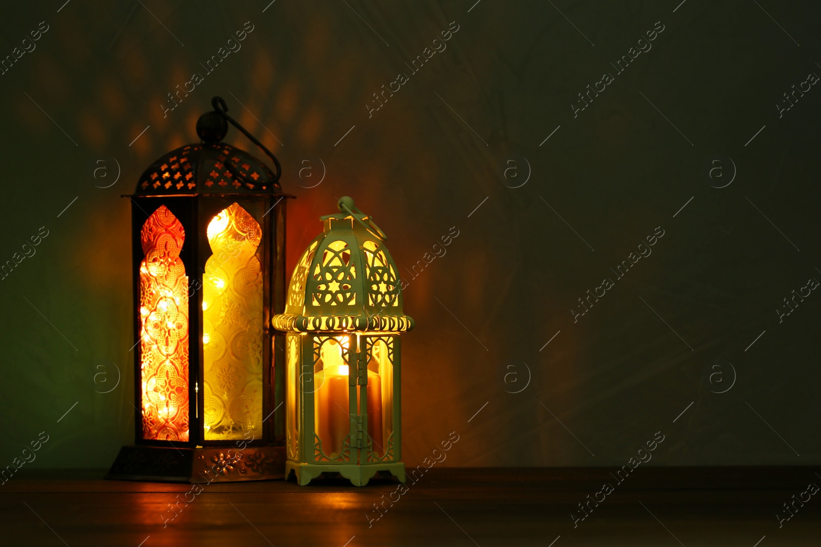 Photo of Decorative Arabic lanterns on table against dark background. Space for text