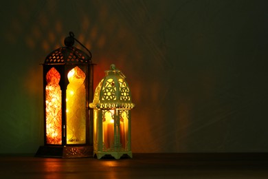Photo of Decorative Arabic lanterns on table against dark background. Space for text