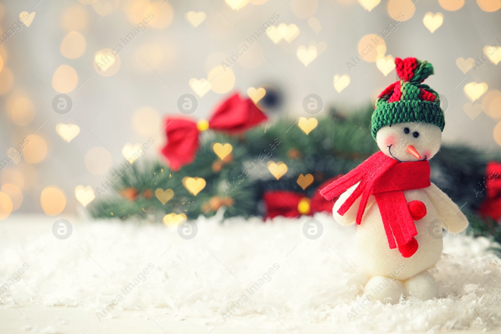 Image of Cute snowman and fir tree branches on snow, bokeh effect. Space for text