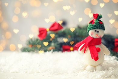 Image of Cute snowman and fir tree branches on snow, bokeh effect. Space for text