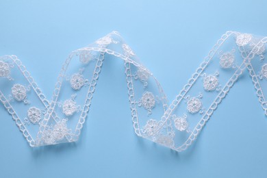 Photo of White lace on light blue background, top view