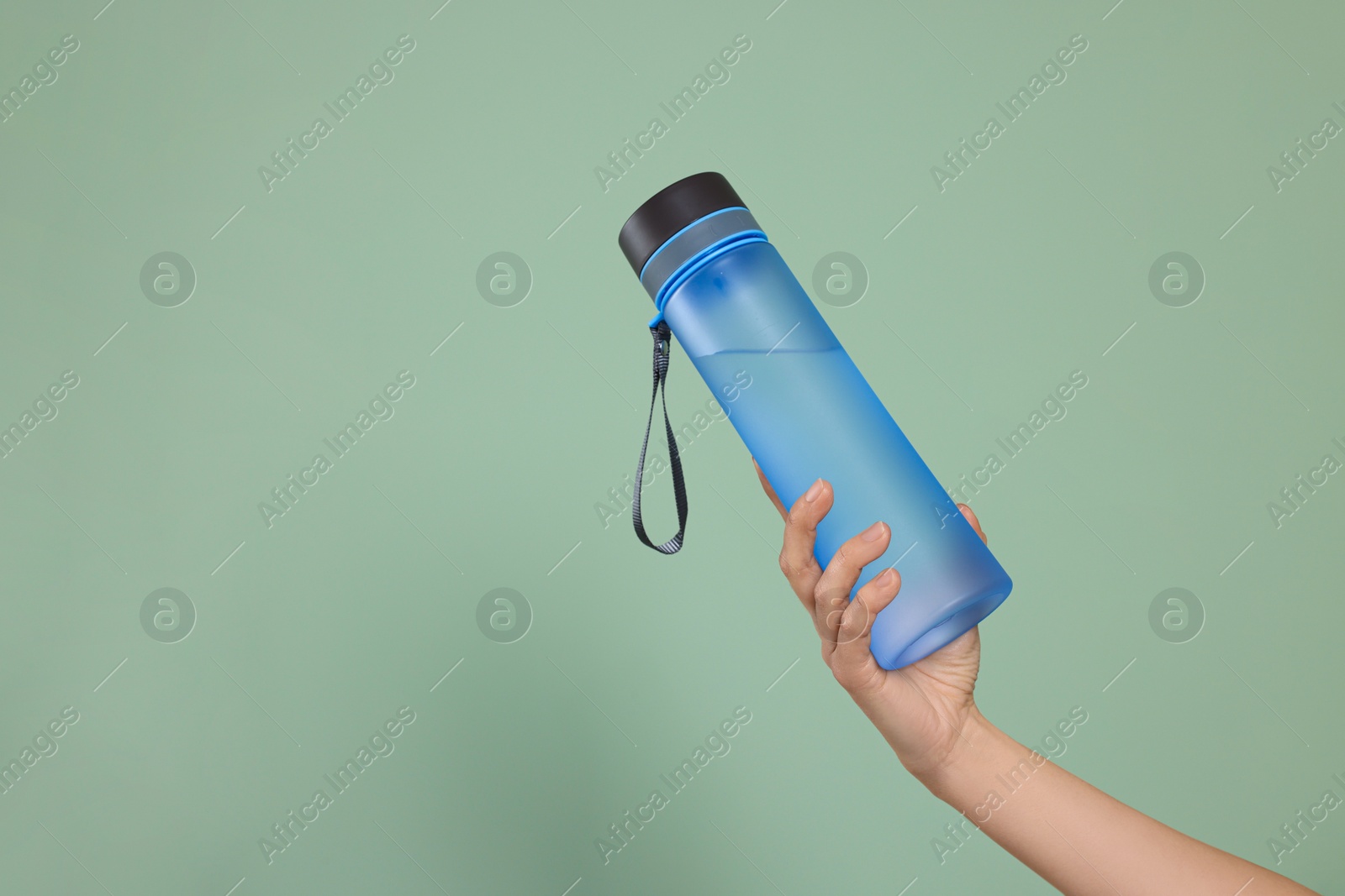 Photo of Woman holding bottle of water on green background, closeup. Space for text