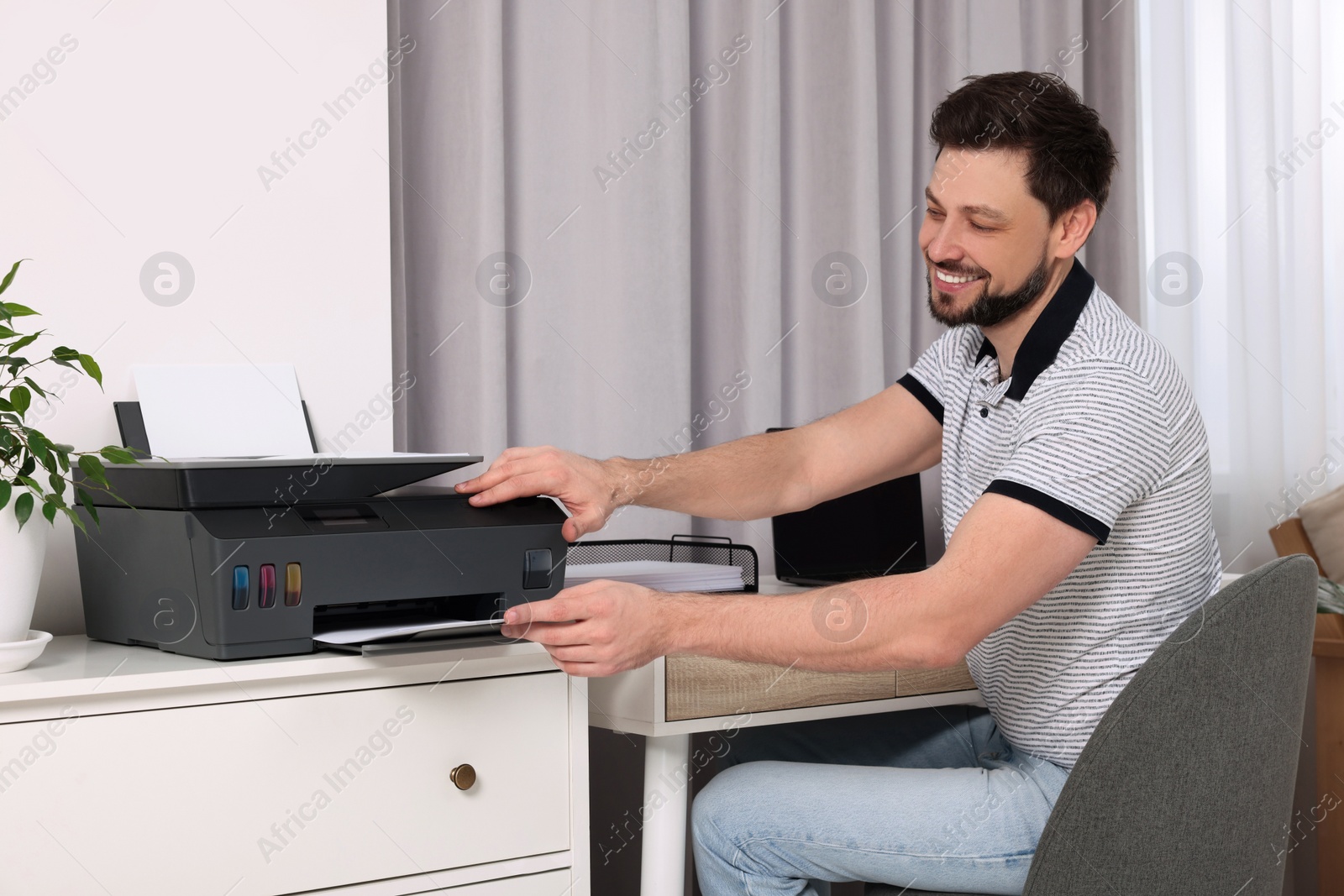 Photo of Man using modern printer at workplace indoors