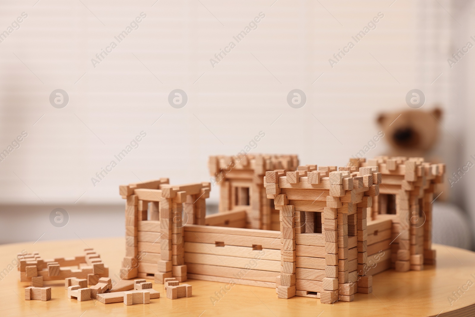 Photo of Wooden fortress and building blocks on table indoors, space for text. Children's toy