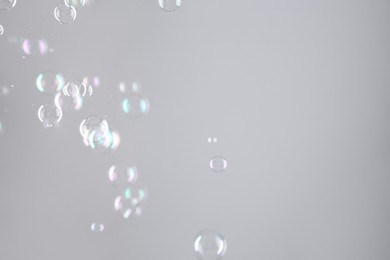 Beautiful transparent soap bubbles on grey background, space for text