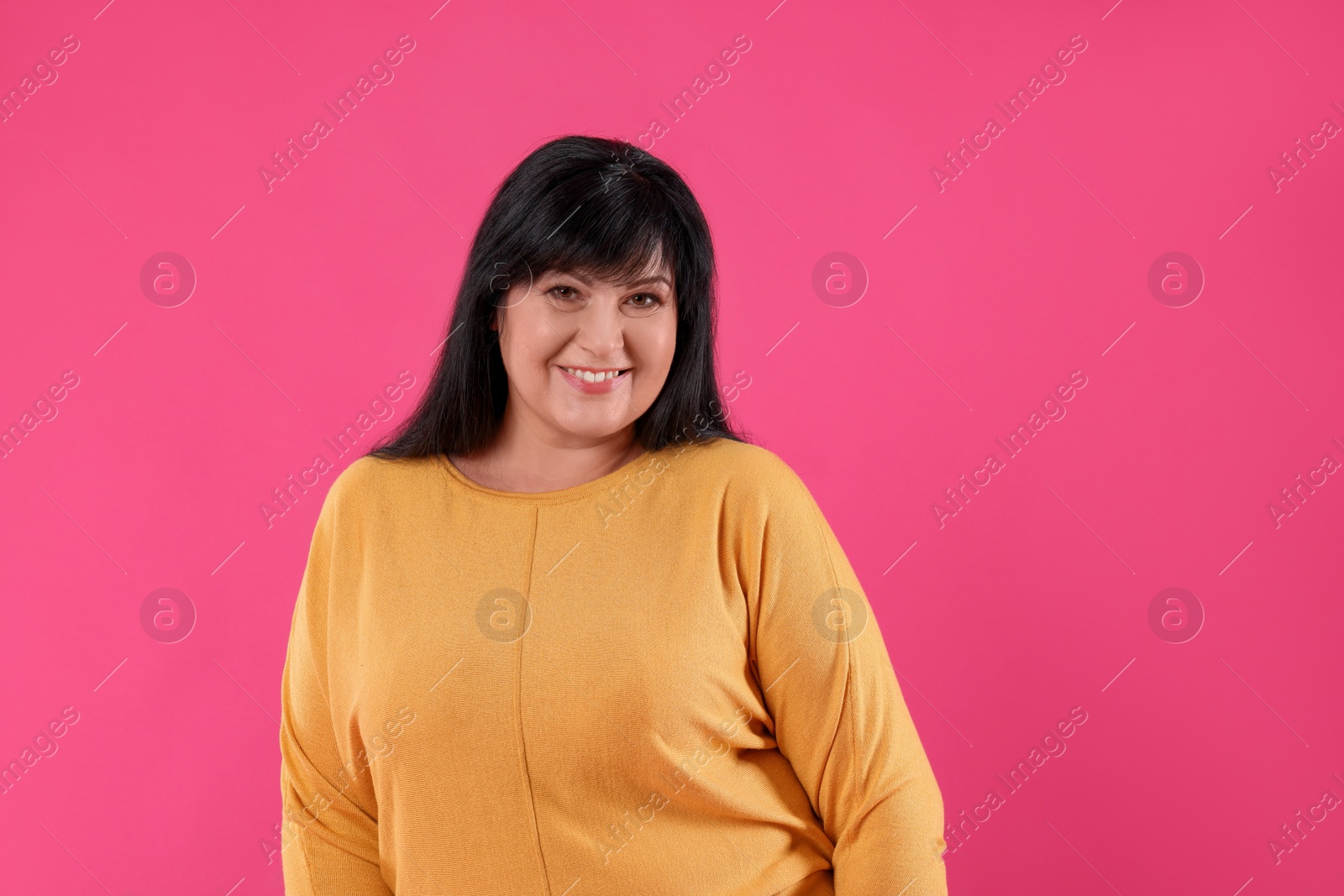 Photo of Beautiful overweight mature woman with charming smile on pink background
