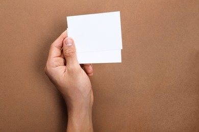 Photo of Man holding sheets of paper on brown background, closeup. Mockup for design