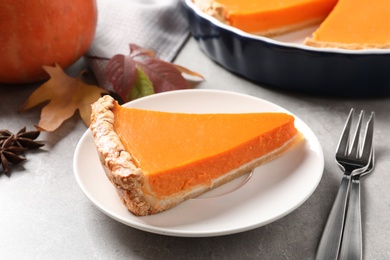 Photo of Plate with piece of fresh delicious homemade pumpkin pie on gray table