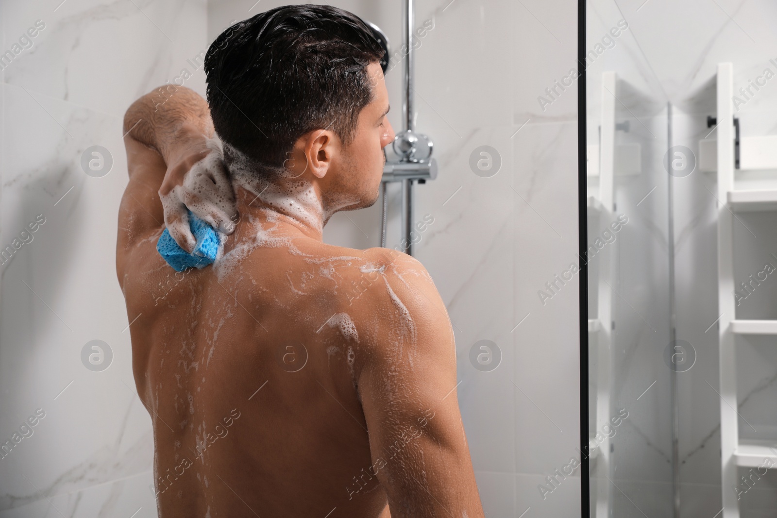 Photo of Handsome man with sponge taking shower at home